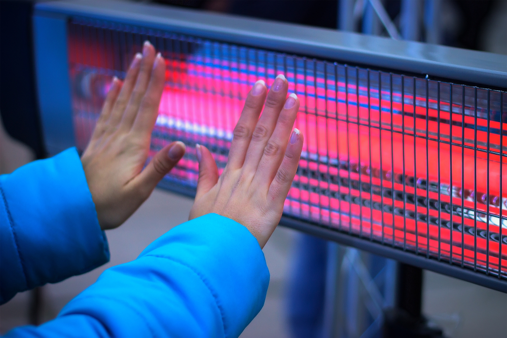 girl warming hands with electric infrared heater
